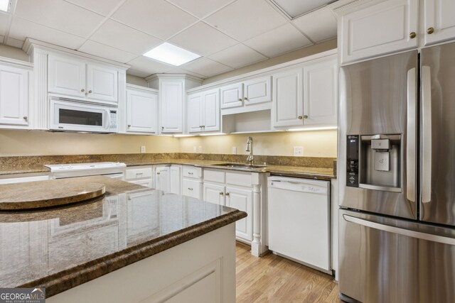 kitchen featuring white cabinets, light wood-type flooring, white appliances, and dark stone counters