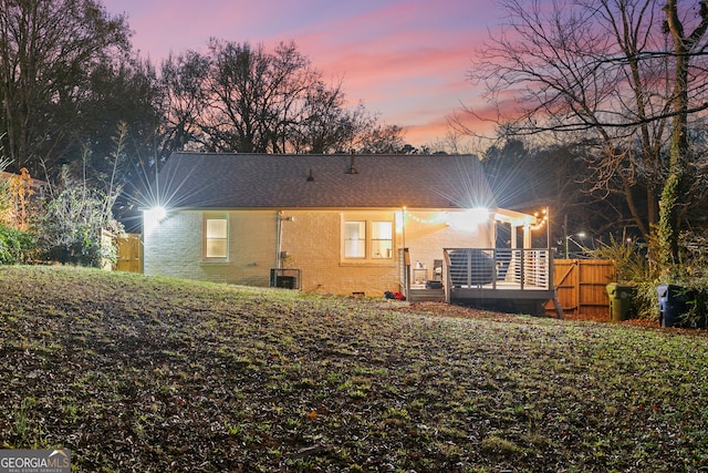 back house at dusk featuring a wooden deck