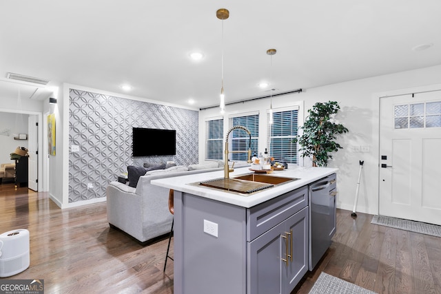 kitchen featuring dishwasher, dark wood-type flooring, a center island with sink, sink, and decorative light fixtures