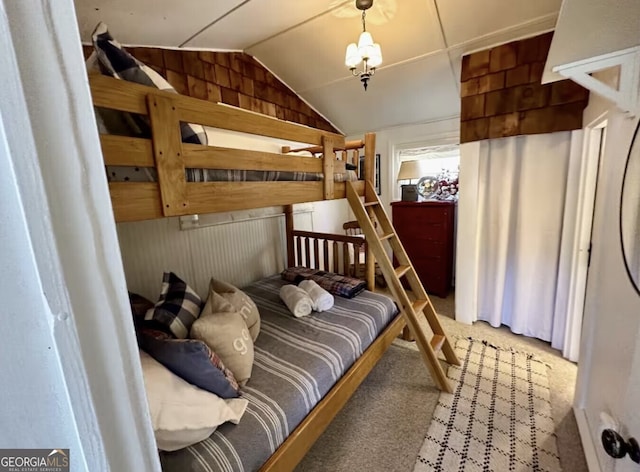 bedroom with carpet flooring, lofted ceiling, wooden walls, and a chandelier