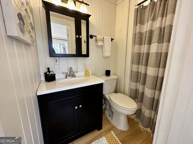 bathroom featuring wood-type flooring, vanity, toilet, and curtained shower