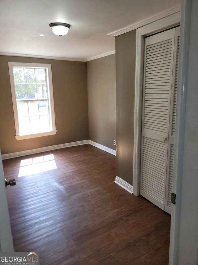 unfurnished bedroom featuring dark hardwood / wood-style flooring, a closet, and crown molding