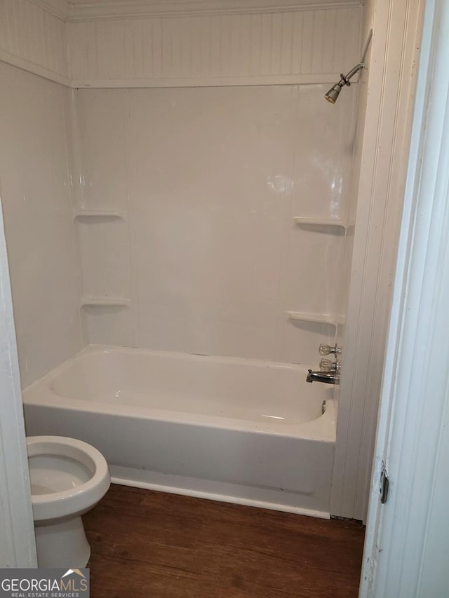 bathroom with wood-type flooring, bathing tub / shower combination, and toilet