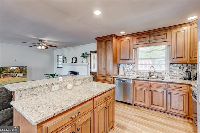 kitchen with a brick fireplace, stainless steel appliances, sink, light hardwood / wood-style flooring, and a center island