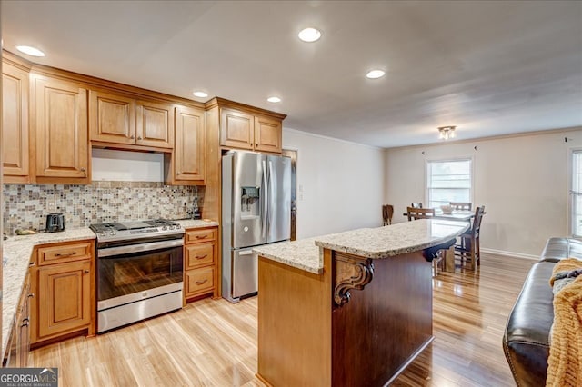 kitchen with a kitchen island, light wood-type flooring, stainless steel appliances, and ornamental molding