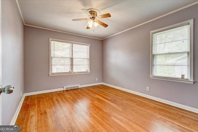 empty room with crown molding, a healthy amount of sunlight, and light hardwood / wood-style floors