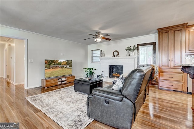 living room with a brick fireplace, ceiling fan, ornamental molding, and light hardwood / wood-style flooring