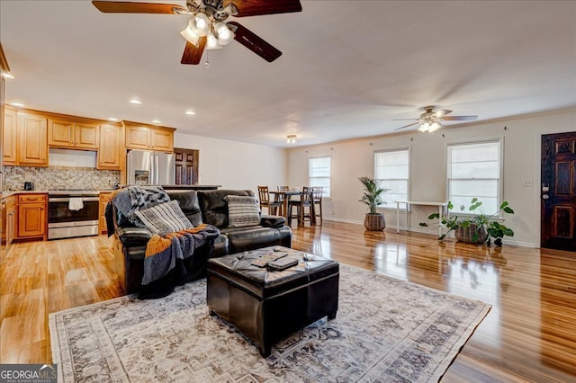 living room with ceiling fan, ornamental molding, and light hardwood / wood-style flooring