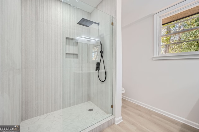 bathroom featuring toilet, wood-type flooring, and tiled shower