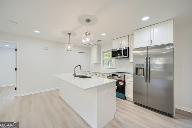 kitchen featuring sink, hanging light fixtures, light hardwood / wood-style floors, white cabinetry, and stainless steel appliances