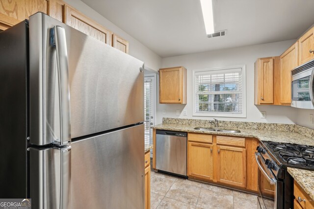 kitchen with light stone counters, sink, and stainless steel appliances