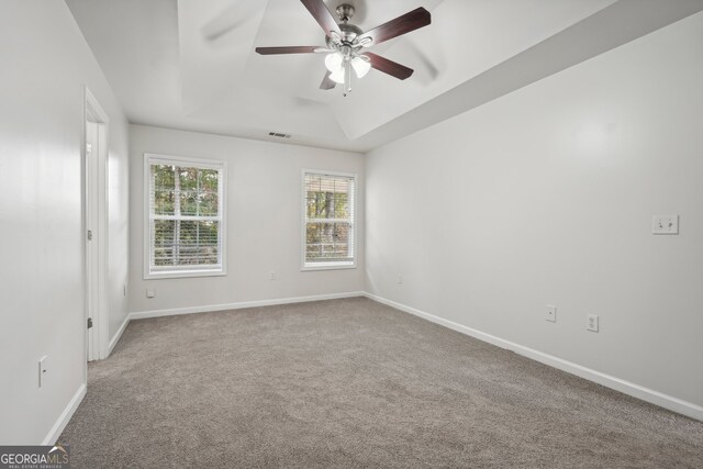 spare room featuring carpet flooring, a tray ceiling, and ceiling fan