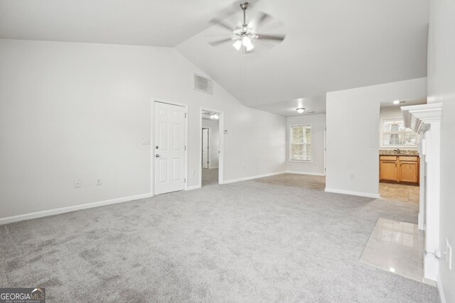 unfurnished living room with light carpet, high vaulted ceiling, and ceiling fan