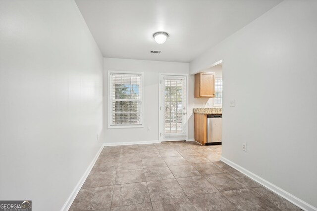 kitchen featuring light brown cabinets, light tile patterned floors, and stainless steel dishwasher