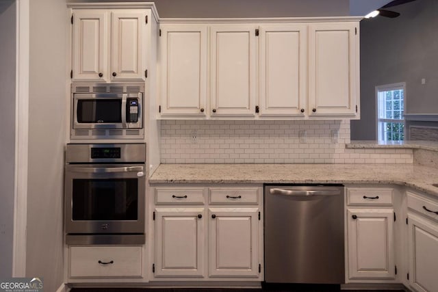 kitchen featuring tasteful backsplash, white cabinetry, light stone countertops, and appliances with stainless steel finishes