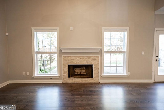 unfurnished living room featuring a wealth of natural light, a fireplace, and dark hardwood / wood-style floors