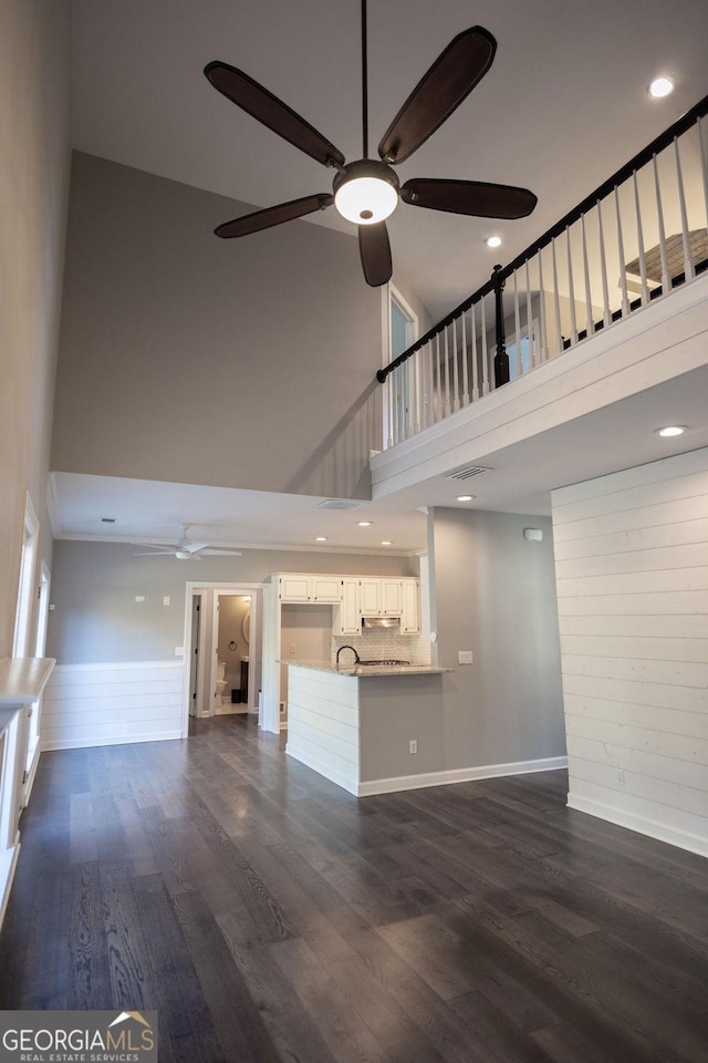 unfurnished living room featuring a towering ceiling, dark hardwood / wood-style floors, ceiling fan, and sink