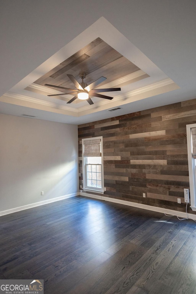 spare room featuring a tray ceiling, wooden walls, dark hardwood / wood-style flooring, and ceiling fan