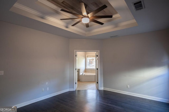 spare room with a raised ceiling, ceiling fan, dark wood-type flooring, and ornamental molding