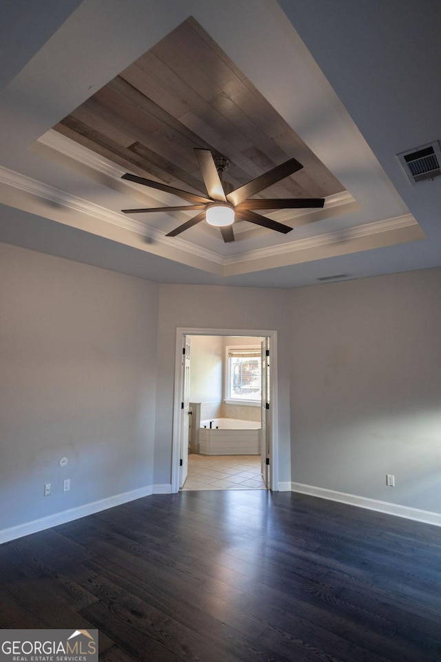 empty room featuring a raised ceiling, crown molding, dark hardwood / wood-style flooring, and ceiling fan