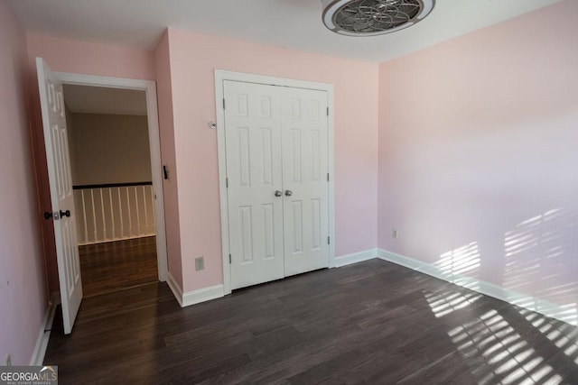 unfurnished bedroom featuring a closet and dark wood-type flooring