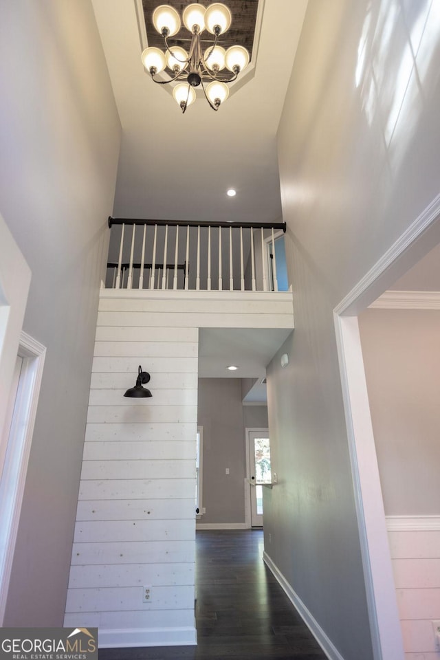 interior space featuring dark hardwood / wood-style floors, a towering ceiling, crown molding, and an inviting chandelier