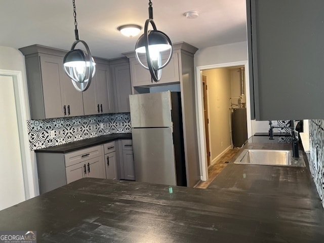 kitchen with stainless steel fridge, hanging light fixtures, gray cabinetry, and sink