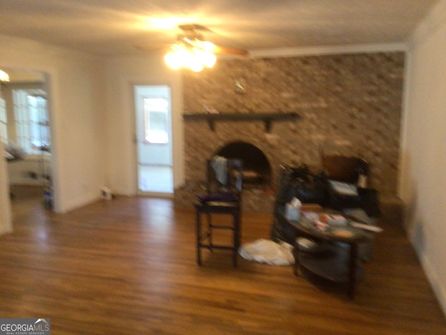 living room with ceiling fan, a fireplace, crown molding, and dark wood-type flooring