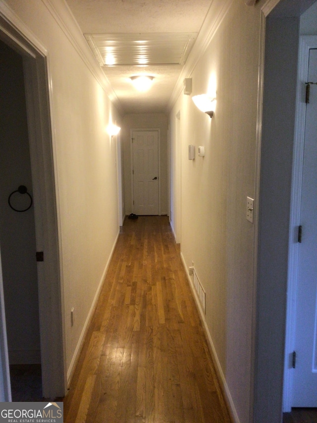 corridor with hardwood / wood-style flooring and ornamental molding