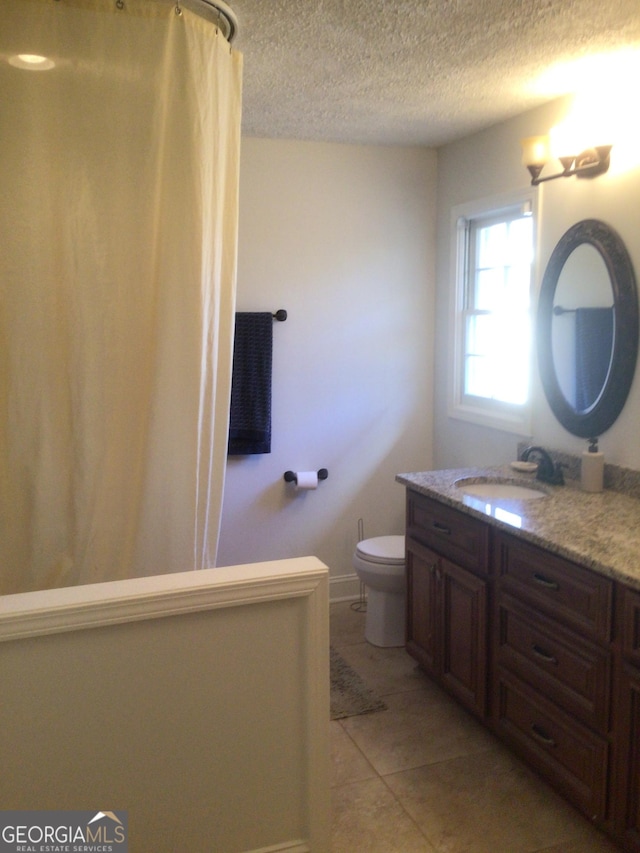 bathroom featuring tile patterned floors, vanity, toilet, and a textured ceiling