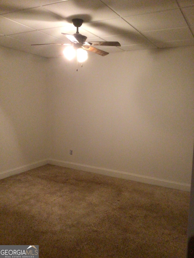 empty room featuring a paneled ceiling, carpet flooring, and ceiling fan