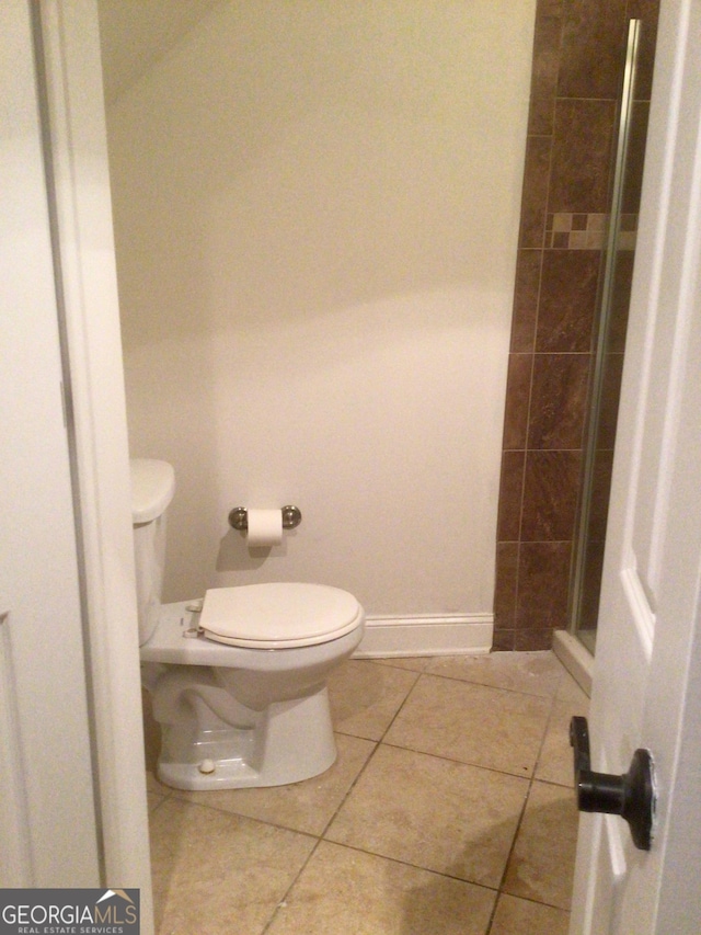 bathroom featuring tile patterned flooring, toilet, and walk in shower