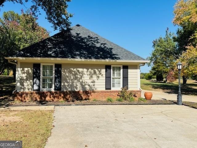 view of front of house featuring brick siding and roof with shingles