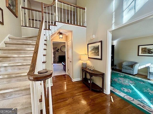 stairs with a towering ceiling, baseboards, and wood finished floors