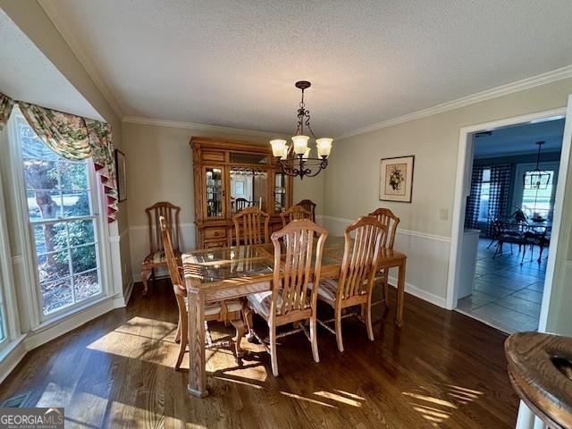 dining area with an inviting chandelier, crown molding, a textured ceiling, and wood finished floors