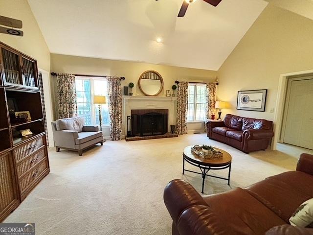 living room with ceiling fan, carpet floors, a fireplace, and high vaulted ceiling