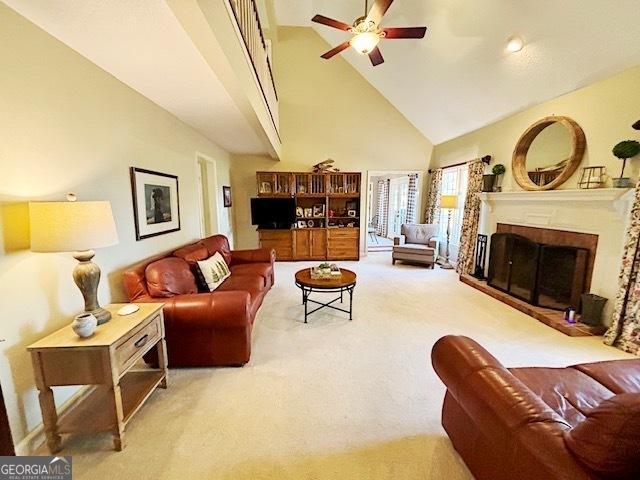 carpeted living area with ceiling fan, high vaulted ceiling, and a fireplace