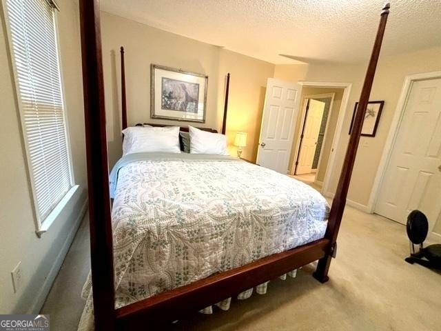 bedroom featuring a textured ceiling, light carpet, and baseboards