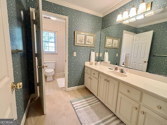 bathroom with toilet, wallpapered walls, crown molding, and vanity