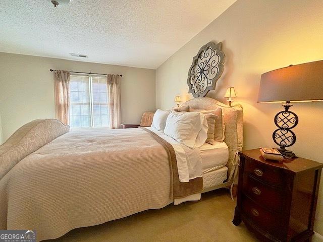 carpeted bedroom featuring visible vents and a textured ceiling