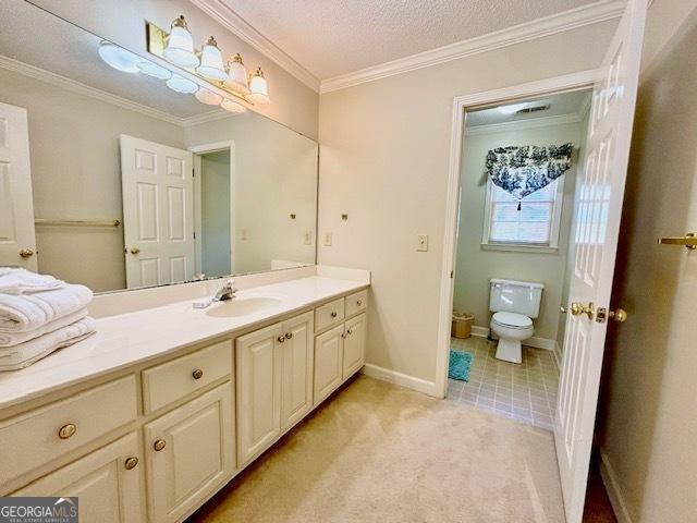 bathroom with a textured ceiling, vanity, toilet, and crown molding