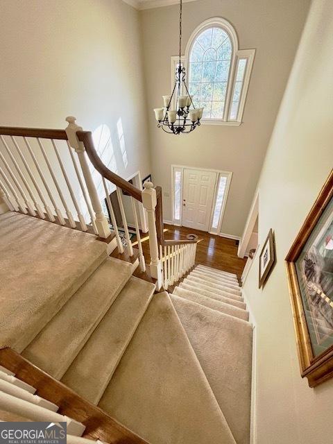 stairs featuring a chandelier, a high ceiling, and wood finished floors