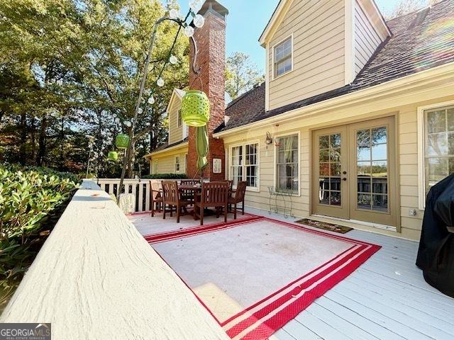 wooden terrace with outdoor dining space and french doors