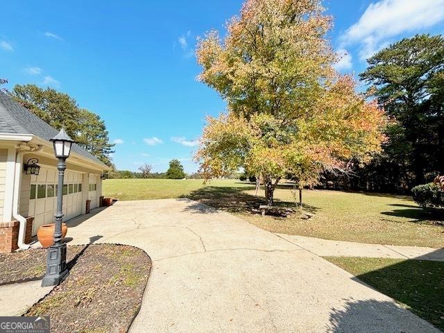 view of yard with a garage and concrete driveway