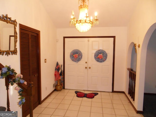 entryway with light tile patterned floors and a notable chandelier