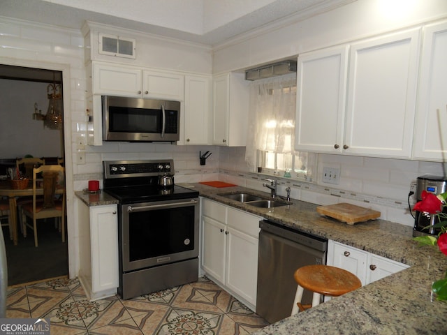 kitchen with sink, white cabinetry, stainless steel appliances, and stone counters