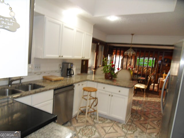 kitchen featuring white cabinets, appliances with stainless steel finishes, kitchen peninsula, and sink