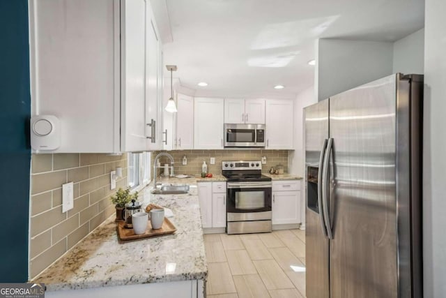 kitchen with light stone countertops, white cabinetry, sink, stainless steel appliances, and backsplash