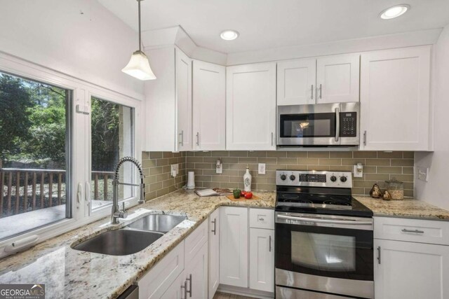 kitchen with sink, pendant lighting, decorative backsplash, white cabinets, and appliances with stainless steel finishes