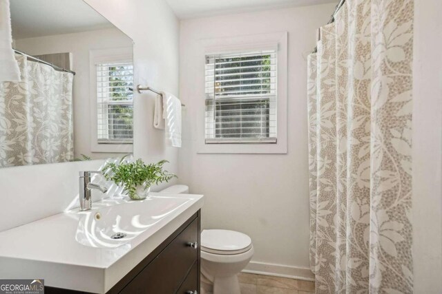 bathroom featuring tile patterned flooring, plenty of natural light, vanity, and toilet